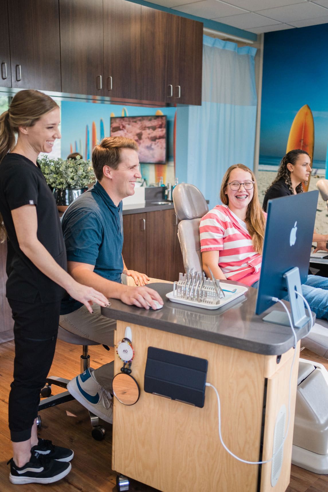 Dr. Kinser and an assistant sharing a laugh with a teen patient in braces at Kinser Orthodontics