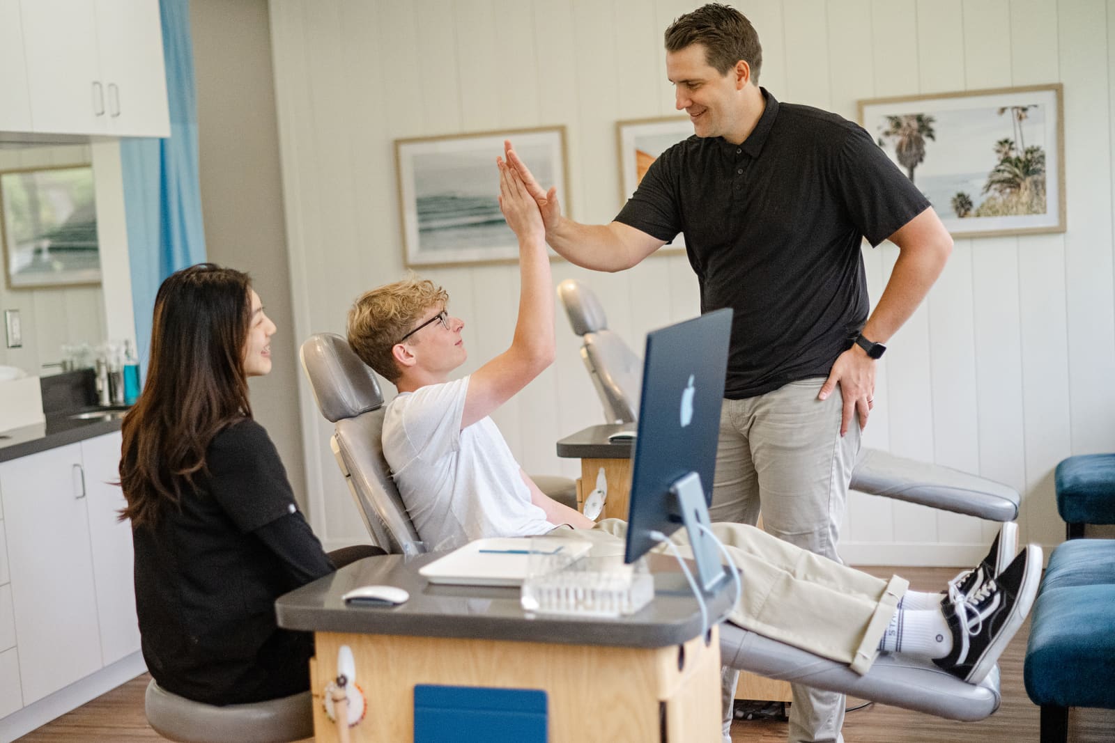 Dr. Kinser high-fiving a teen patient in the treatment chair