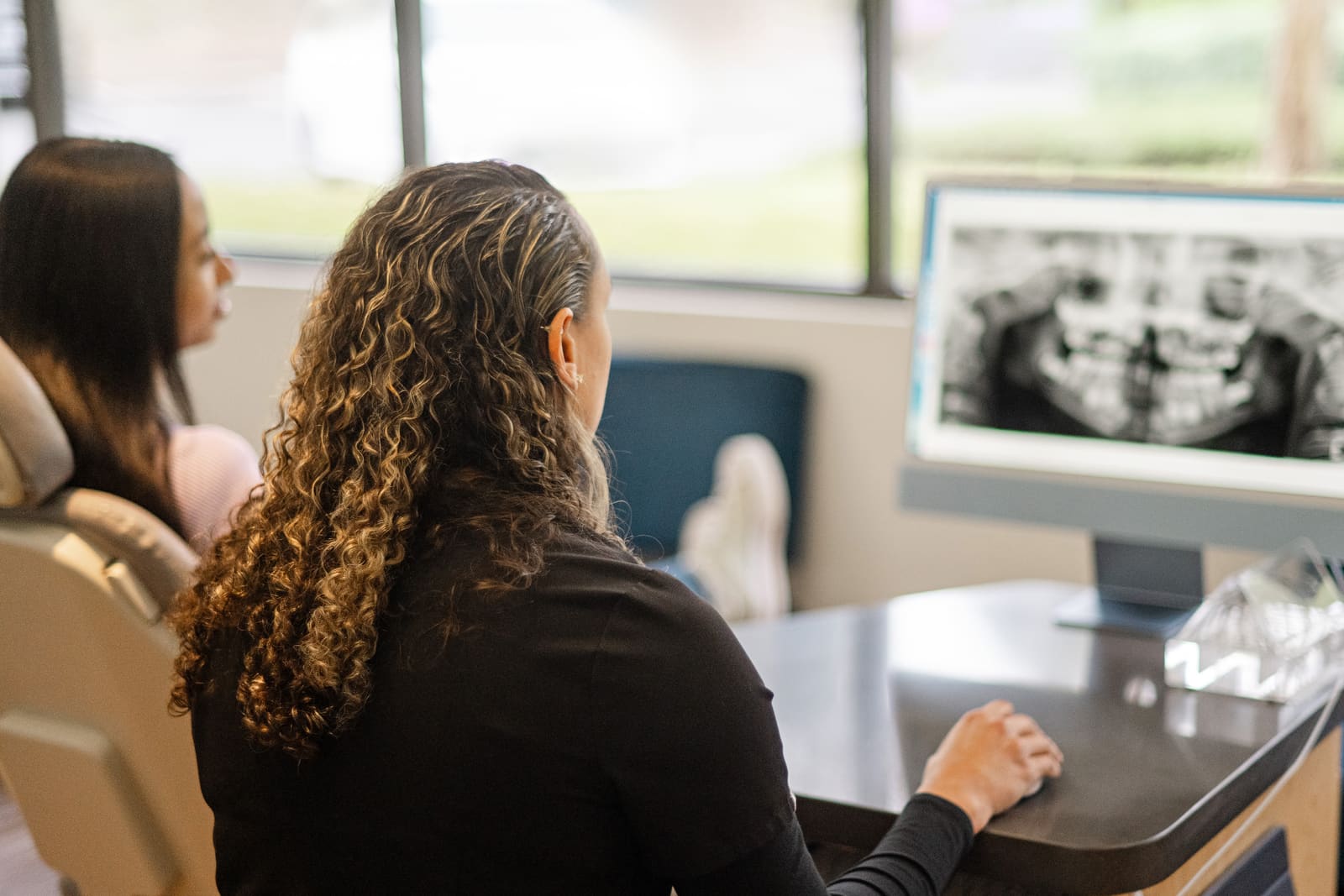 A Kinser Orthodontics team member reviewing a panoramic X-ray with an adult patient