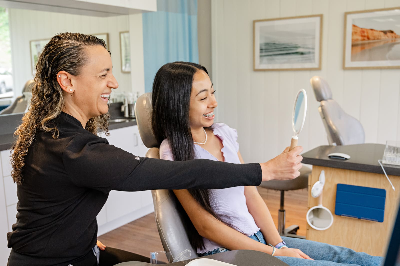 A Kinser team member showing a smiling patient her new smile in the mirror