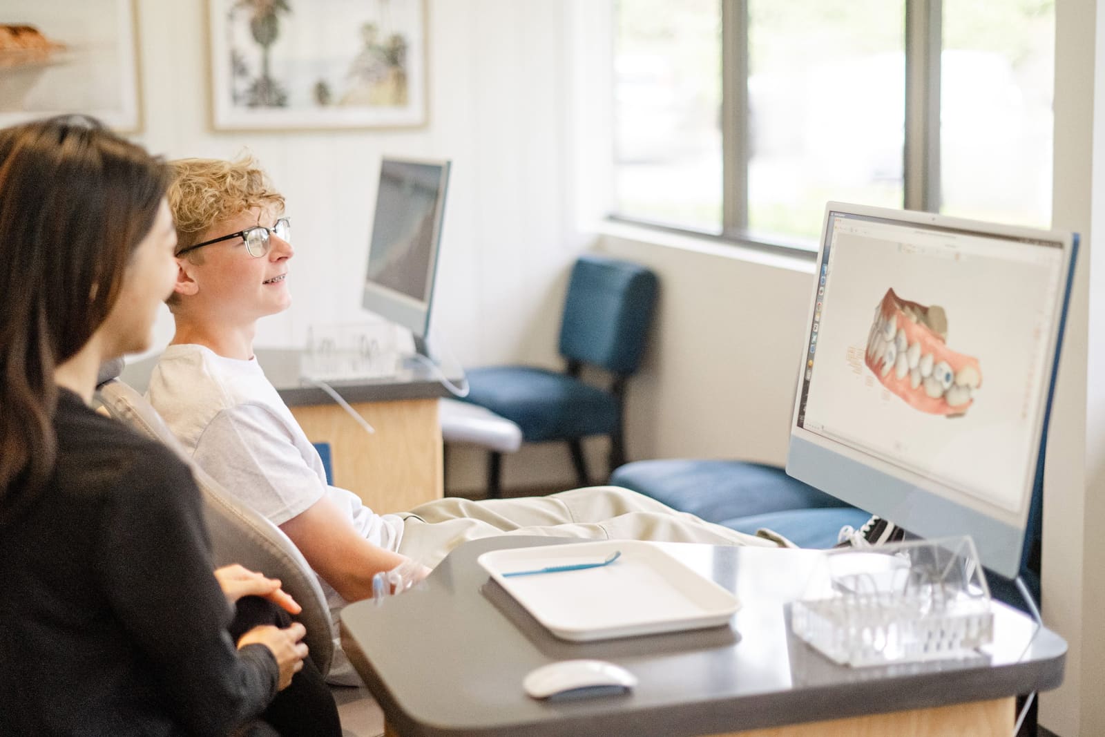 A teen patient smiling at a 3D scan of his teeth on screen