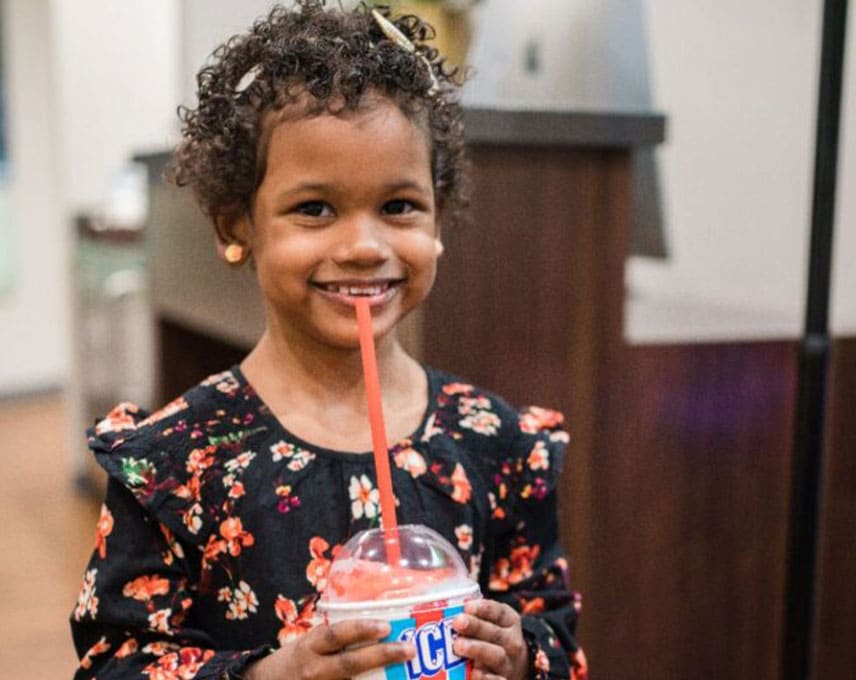 A young patient smiling over an Icee in the Kinser Orthodontics office